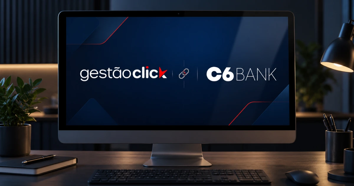 Monitor sobre uma mesa de escritório mostrando os logotipos do GestãoClick e do C6 Bank ligados por um ícone de corrente.