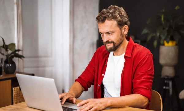 Empresário usando notebook sobre uma mesa em ambiente de escritório particular para Conciliação bancária em menos de 1h por semana.