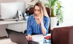 Como contratos impactam retenção de tributos Mulher empresária trabalhando em seu notebook sobre uma mesa em ambiente de escritório sobre Como contratos impactam retenção de tributos.