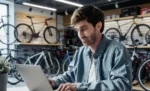 Anexos do Simples Nacional: descubra em qual a sua empresa se enquadra Dono de oficina e loja de bicicletas trabalhando em seu notebook sobre Anexos do Simples Nacional: descubra em qual a sua empresa se enquadra dentro de seu estabelecimento.