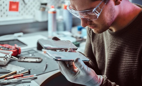 Como precificar serviços de assistência técnica: cálculo de mão de obra, peças e margem Profissional de assistência técnica fazendo reparos em celulares em sua bancada de trabalho representando: Como precificar serviços de assistência técnica: cálculo de mão de obra, peças e margem