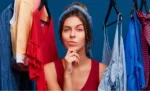 Markup para loja de roupas: como calcular o preço de venda e cobrir todos os custos Empreendedora no meio das araras de roupas de sua loja representando: Markup para loja de roupas: como calcular o preço de venda e cobrir todos os custos