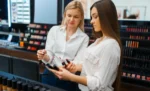 Sistema para loja de cosméticos e beleza: como controlar estoque, PDV e faturamento Duas mulheres olhando e conversando sobre produtos de maquiagem no corredor de uma loja de cosméticos representando: Sistema para loja de cosméticos e beleza: como controlar estoque, PDV e faturamento.
