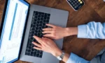 Como controlar contratos recorrentes no GestãoClick: guia de configuração Profissional feminino usando notebook para controlar contratos recorrentes no GestãoClick.