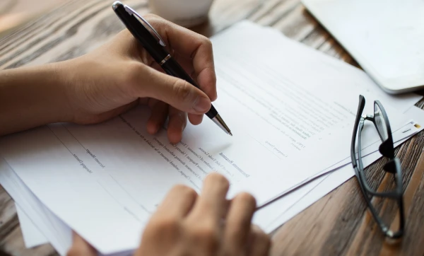 CNPJ irregular ou inativo: o que significa, como acontece e como regularizar Escrevendo em um papel sobre a mesa, representando: CNPJ irregular ou inativo: o que significa, como acontece e como regularizar