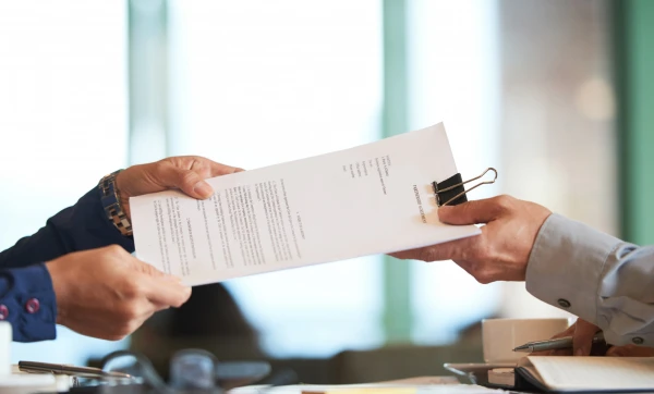 Contratos com fornecedores: cláusulas essenciais para se proteger de atrasos e prejuízos Papel segurado por duas pessoas em um escritório, representando: Veja quais cláusulas protegem sua empresa de atraso, defeito e calote de fornecedor, e como o GestãoClick organiza esse relacionamento na prática.
