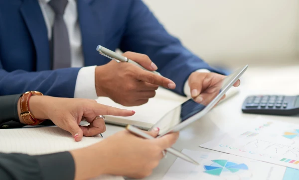 Compliance fiscal para microempresa: o que é, por que importa e como implementar do zero Duas pessoas reunidas em uma mesa analisando documentos representando Compliance fiscal para microempresa: o que é, por que importa e como implementar do zero