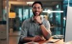 Parcelamento de débitos do Simples Nacional: como fazer e regularizar Homem sorridente em seu local de trabalho, representando: Parcelamento de débitos do Simples Nacional: como fazer e regularizar