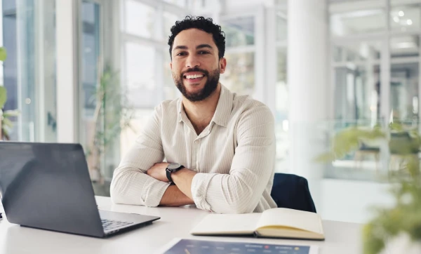 Imposto seletivo: quando as alíquotas serão definidas? Homem sentado de braços cruzados de frente para mesa com seu notebook e seu caderno de anotações representando: Imposto seletivo: quando as alíquotas serão definidas